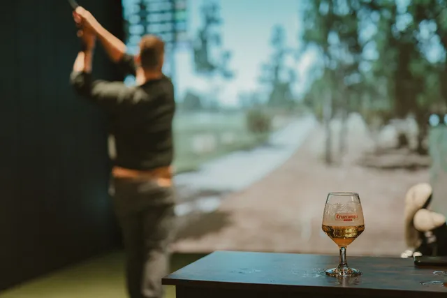 A golfer swinging in a bay, a pint waiting on the table