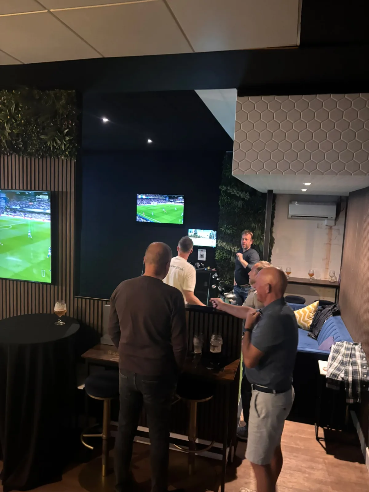 The first floor bar with TV screens and a simulator bay, guests gathered at the tables