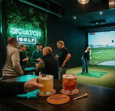 Guests enjoying drinks under the SKRATCH Golf neon sign