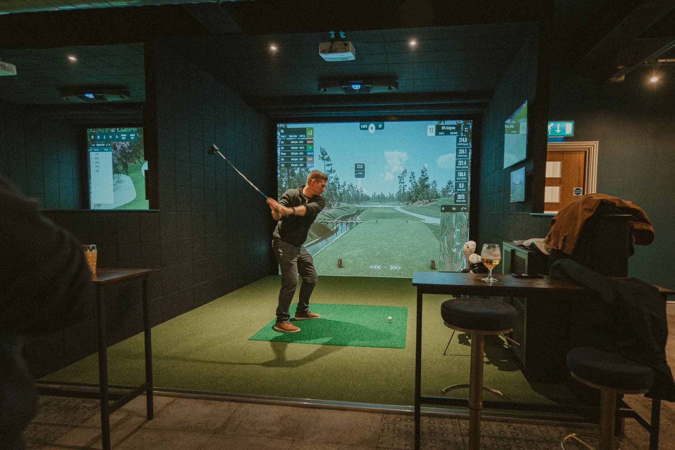 A player mid-swing in a SKRATCH Golf simulator bay