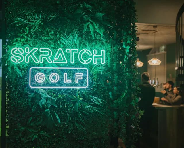 SKRATCH Golf neon sign against a living-plant wall