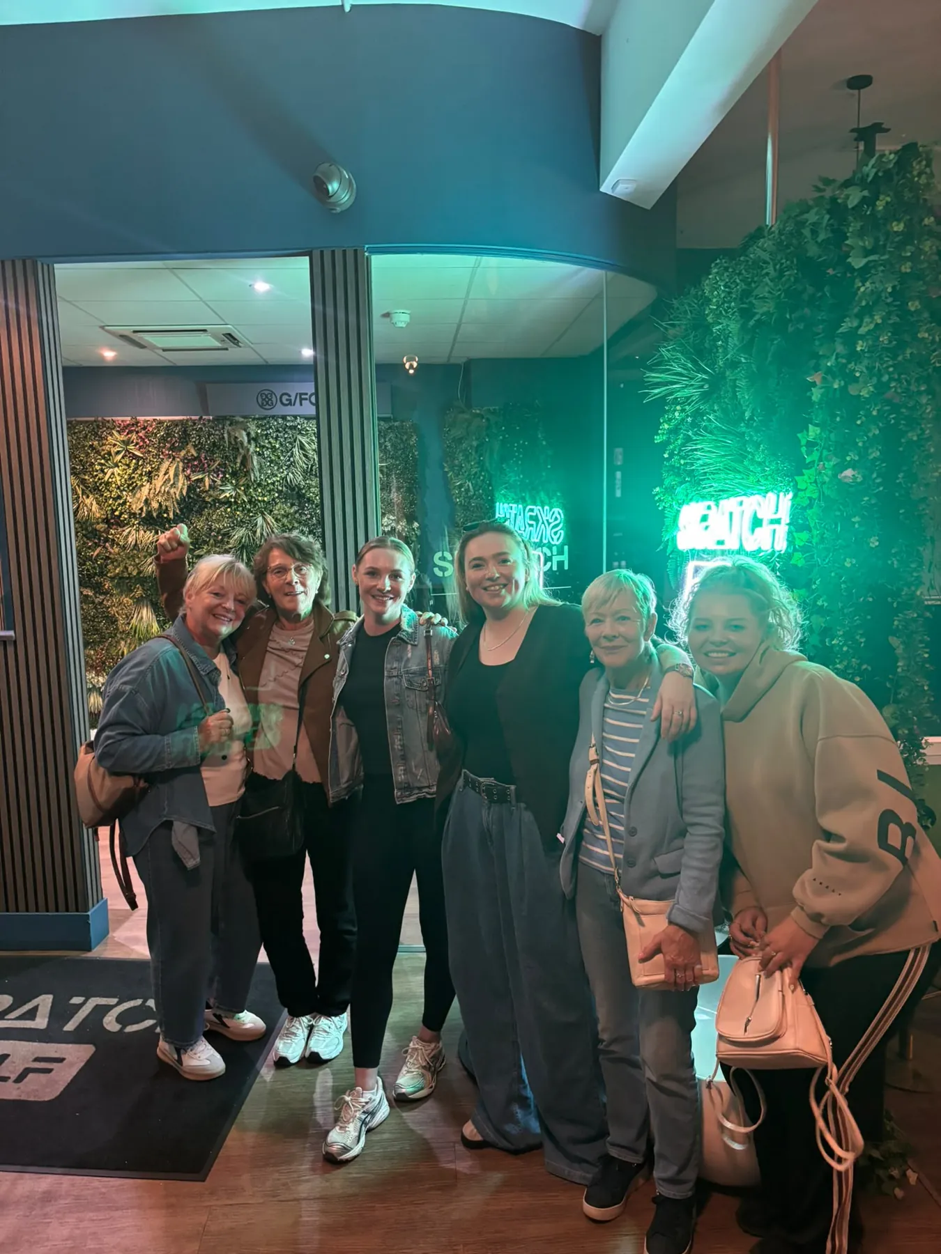 A group of friends at the SKRATCH entrance under the neon sign