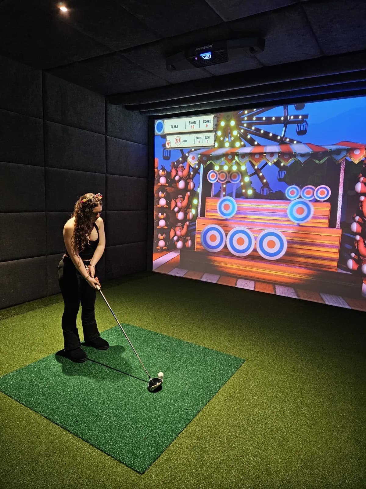 A first-time player lining up a shot at a colourful target game on the simulator screen